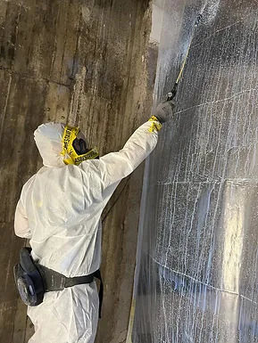 Rivout Group utför asbestsanering av en vägg med skyddsutrustning